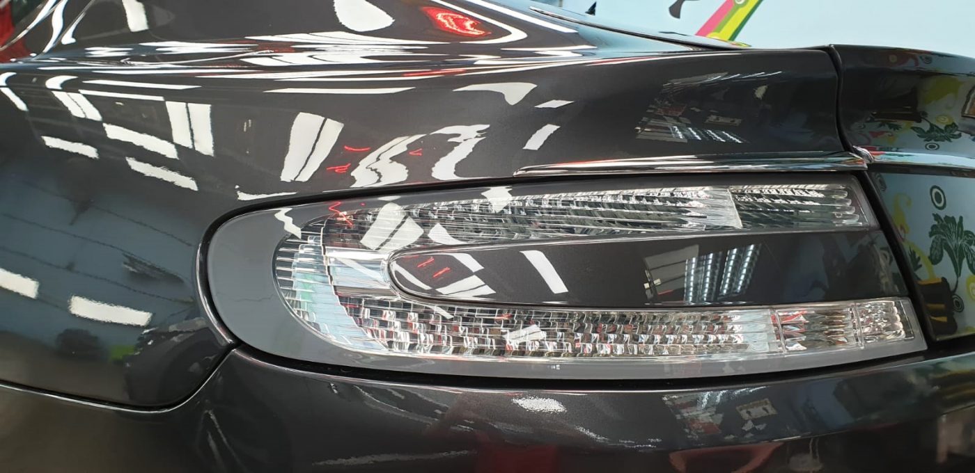 The coated bonnet of the Aston Martin Rapide under workshop lighting.