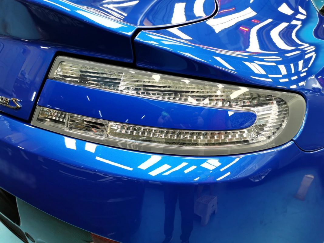 The coated bonnet of the Aston Martin V8 under workshop lighting.