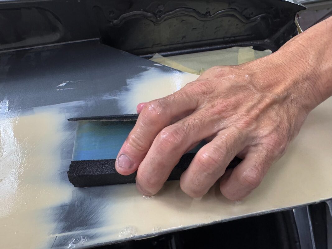 Wet-sanding the body of the Audi A3 to smooth the surface.