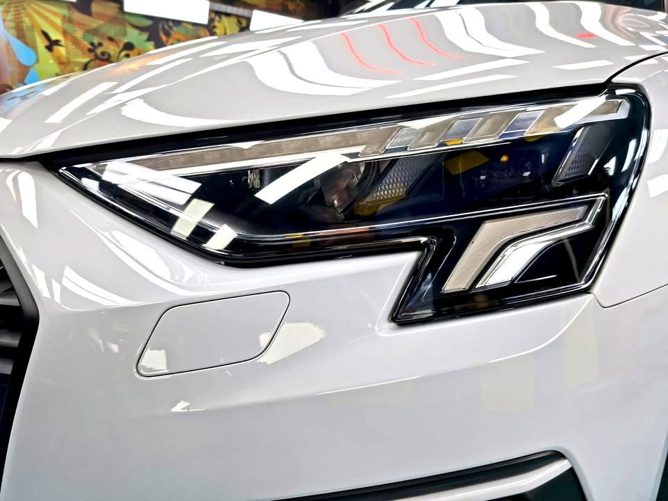 Close view of the Audi A3 headlight and white front bumper.