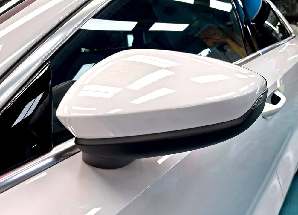 White wing mirror on the Audi A3 with the workshop lights reflected.