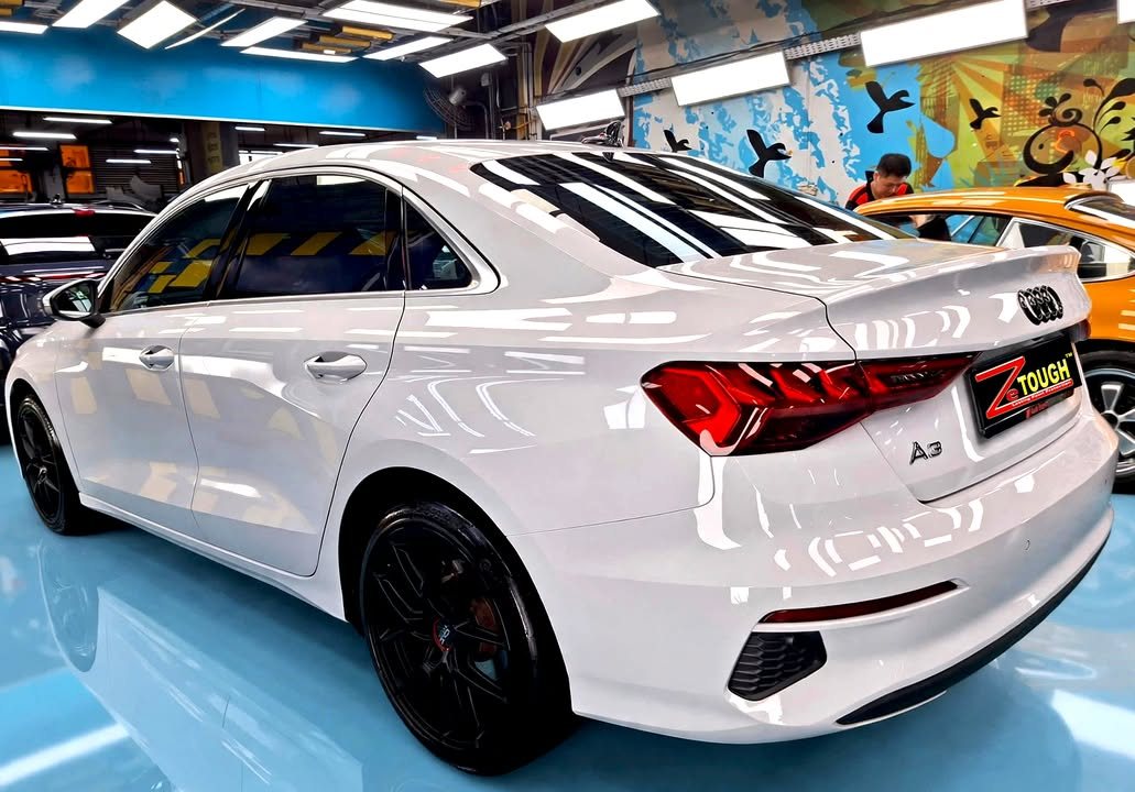 Rear three-quarter view of the white Audi A3 sedan with a ZeTough plate.