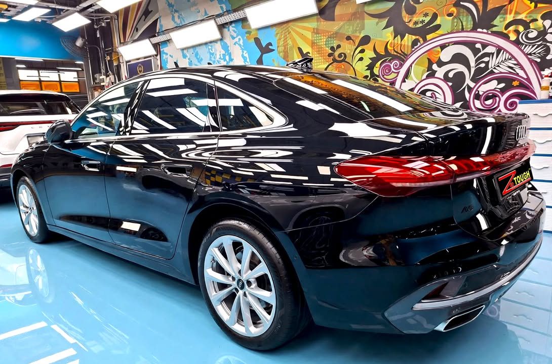 Rear three-quarter view of the black Audi A5 showing the tail lights and silver alloy wheel.