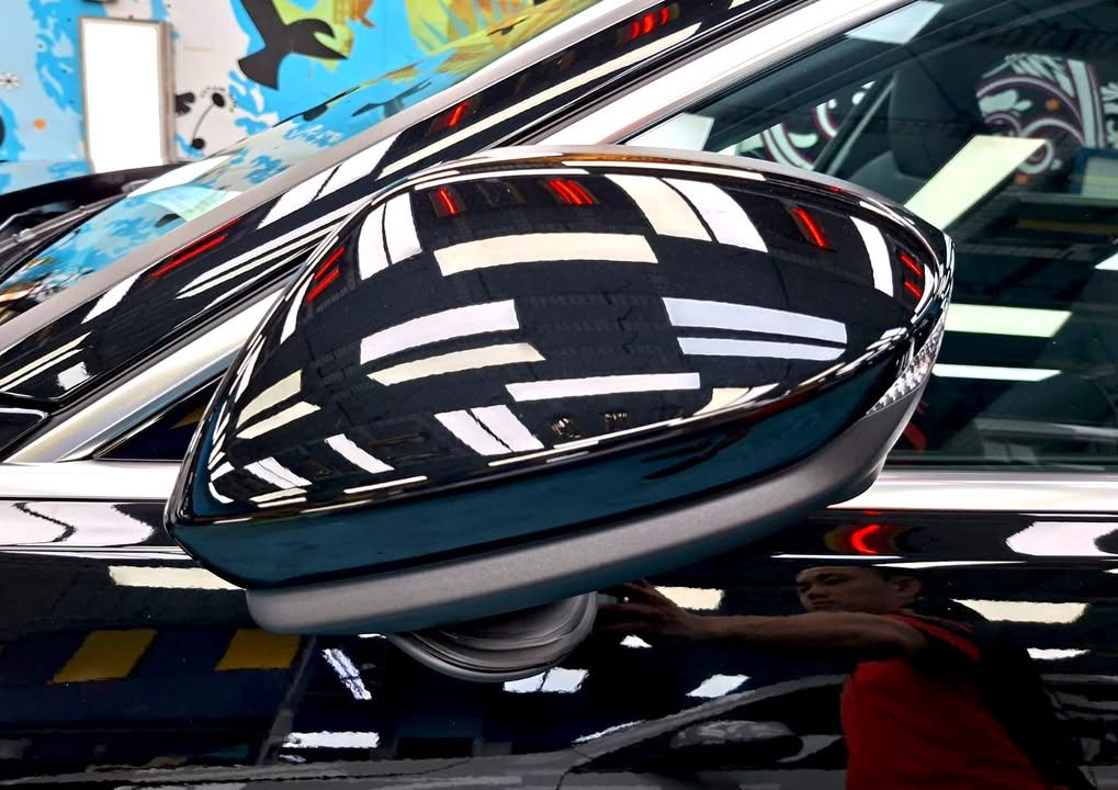 Black side mirror cap with sharp reflections of the ceiling lights.