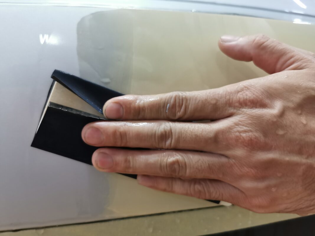 Wet-sanding a panel on the Audi A6 to bring the surface smooth and level.