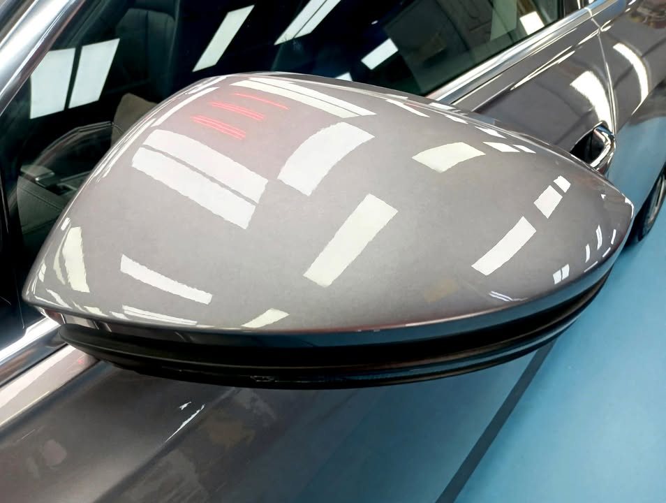 Grey side mirror cap with reflections of the ceiling lights.