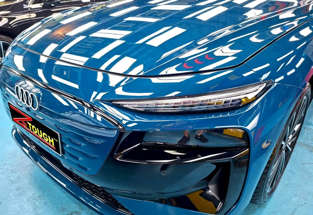 Front of the blue A6 with ceiling lights reflected across the bonnet.
