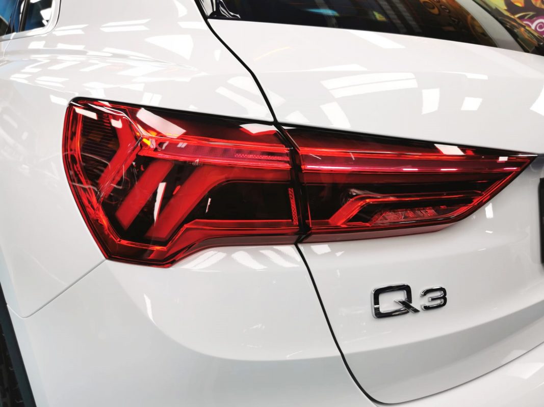 The coated bonnet of the Audi Q3 under workshop lighting.