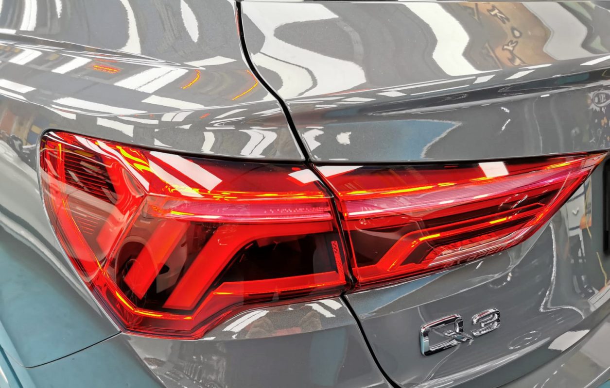 The coated bonnet of the Audi Q3 Sportback under workshop lighting.