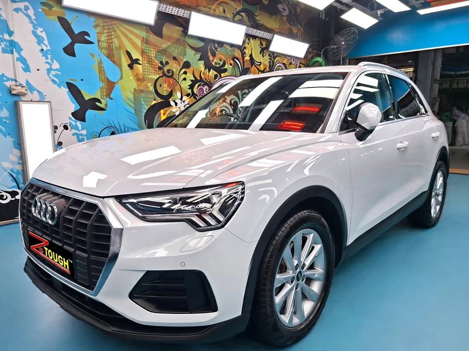 White Audi Q3, front three-quarter view, in the Revol Carz workshop after coating.
