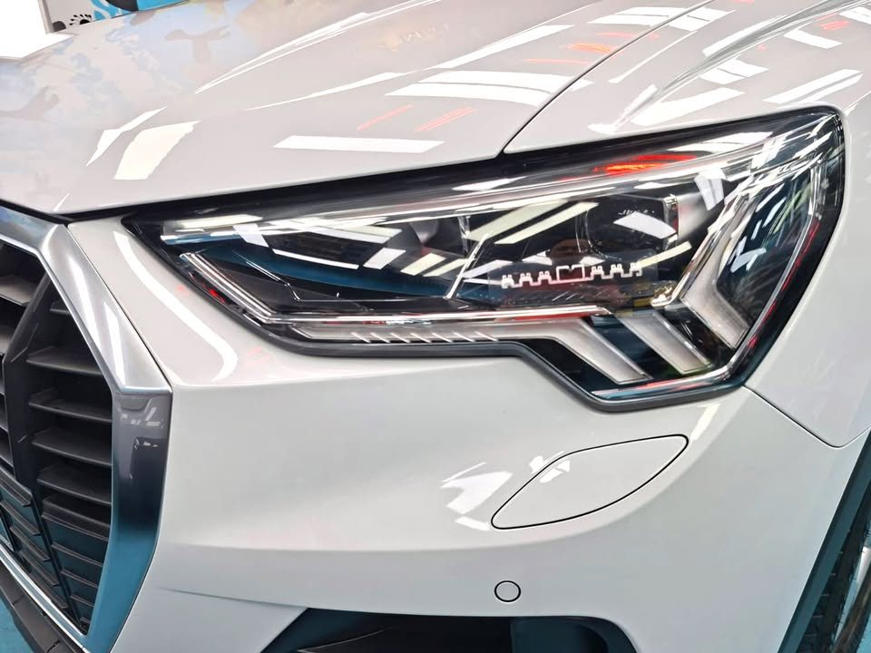 Close-up of the Audi Q3 LED headlight and white front wing.