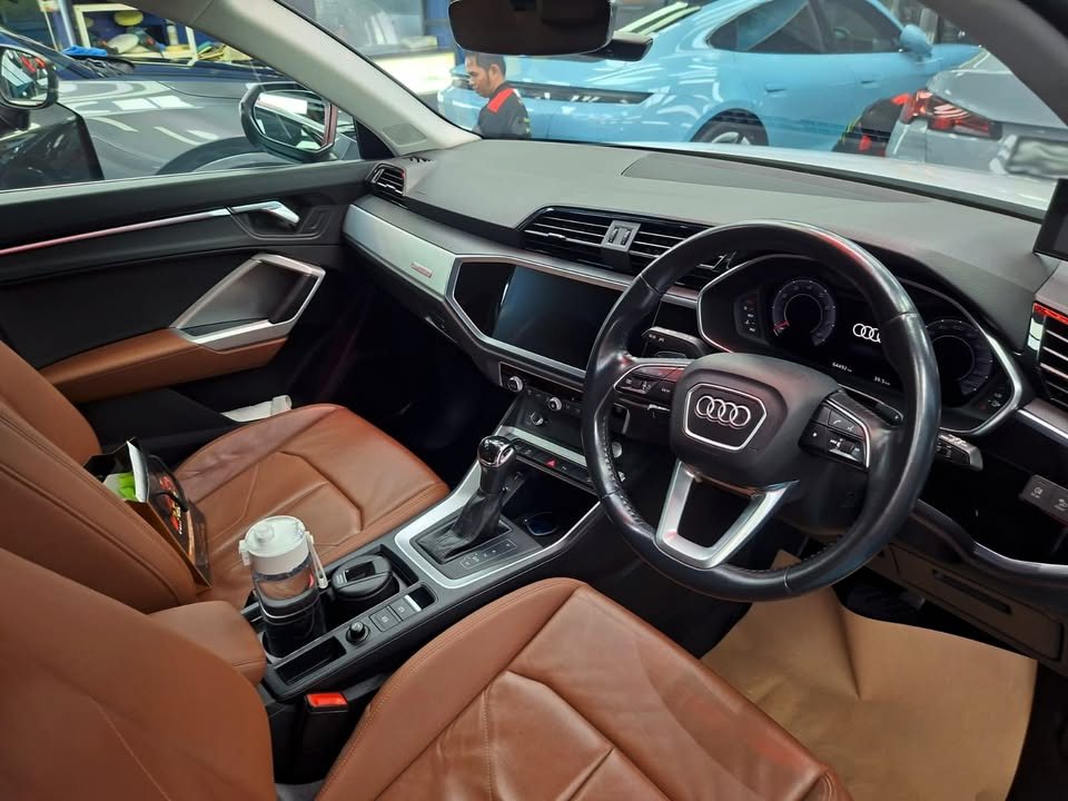 Audi Q3 cabin with tan leather seats, steering wheel and dashboard.