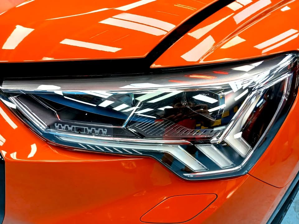 Close-up of the Audi Q3 LED headlamp beside the orange front wing.