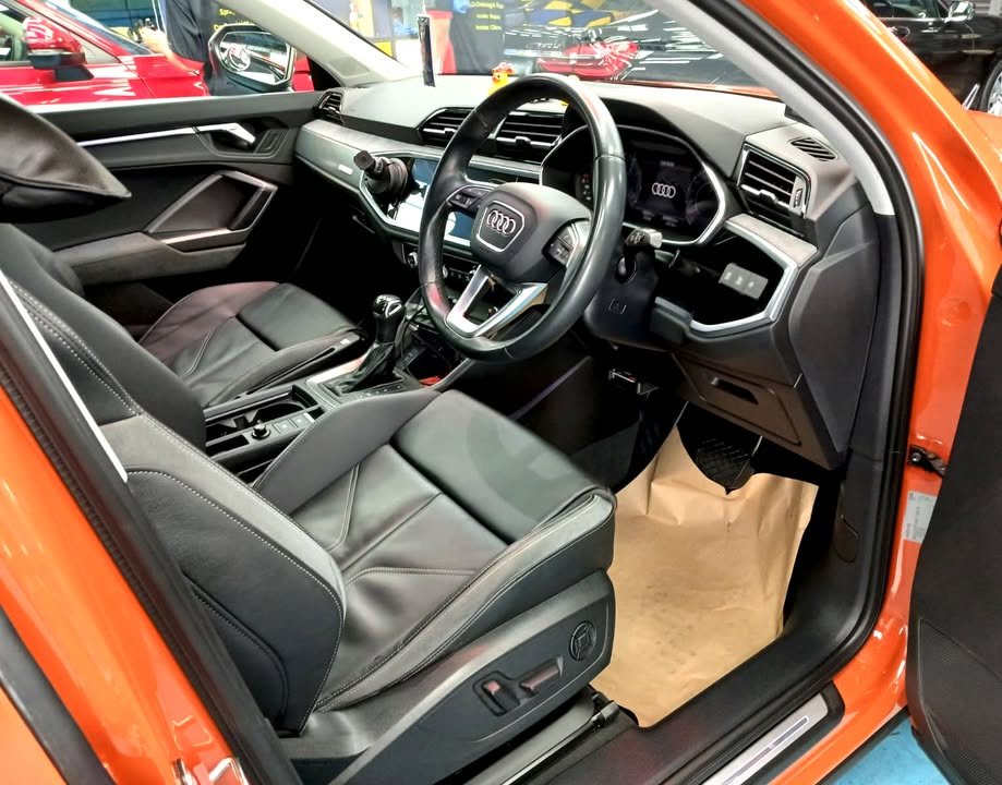 Audi Q3 interior with black leather seats and steering wheel.