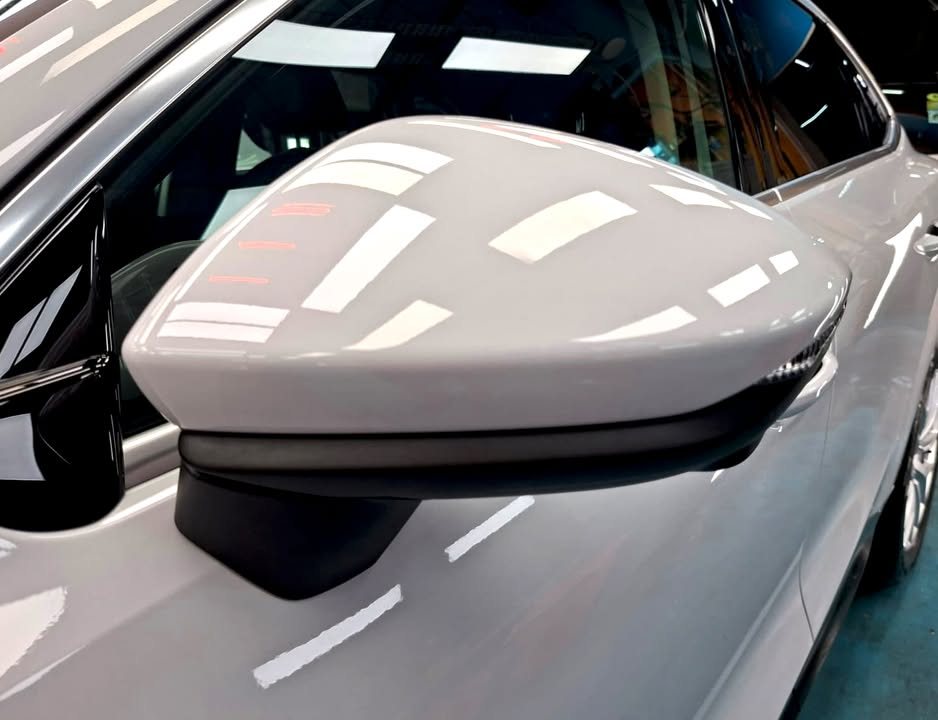 White wing mirror on the Audi Q3 reflecting the workshop lights.