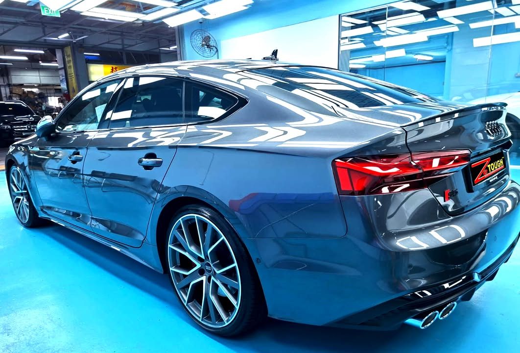 Rear three-quarter view of the grey Audi S5 Sportback showing the tail lights and quad exhausts.