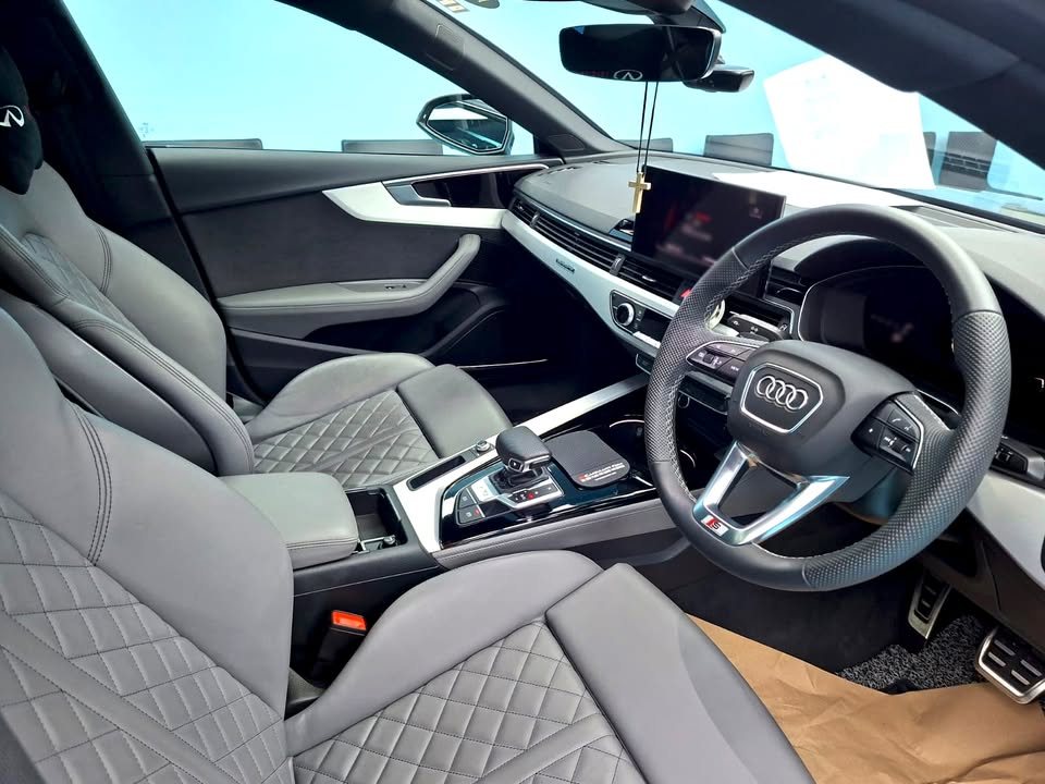Interior of the Audi S5 with grey quilted seats, steering wheel and dashboard.