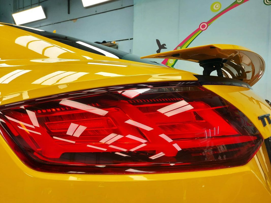 The coated bonnet of the Audi TT under workshop lighting.