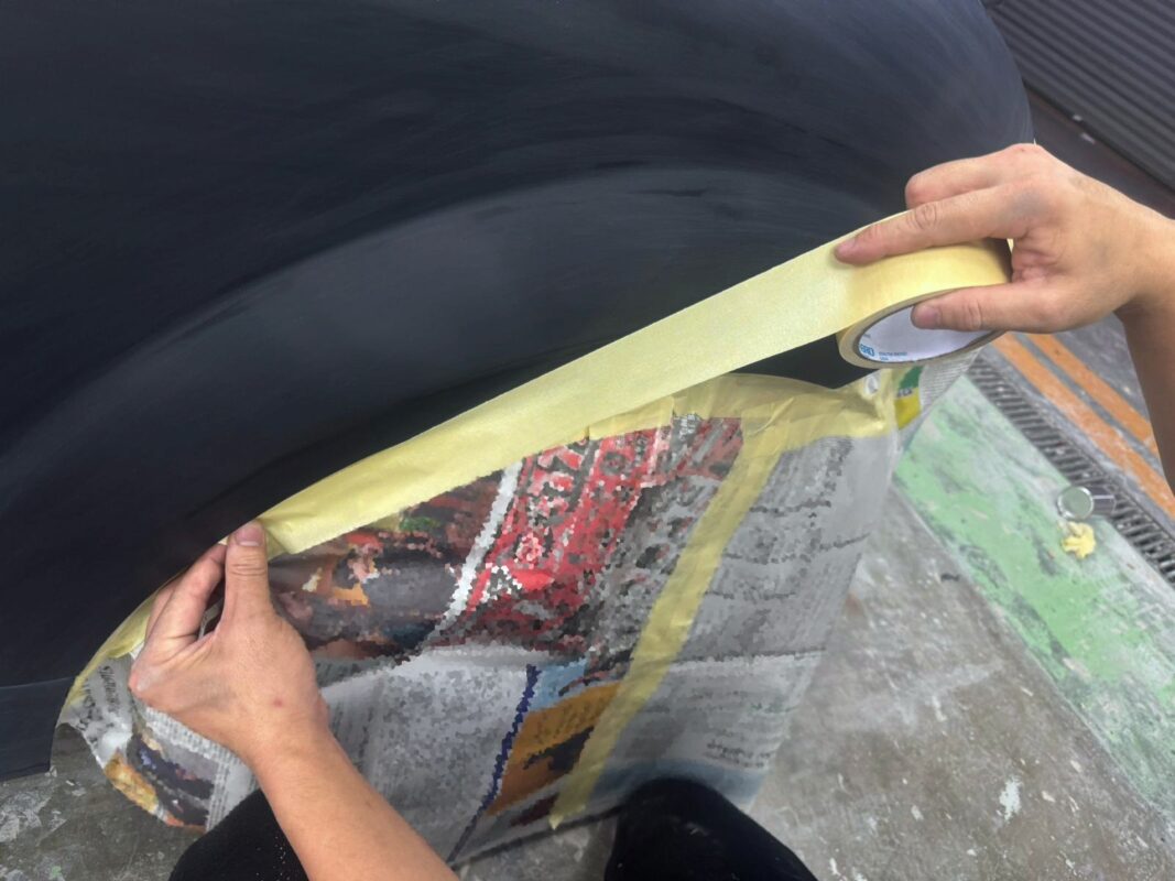 Hand-sanding body filler on a front fender of the Audi TT.