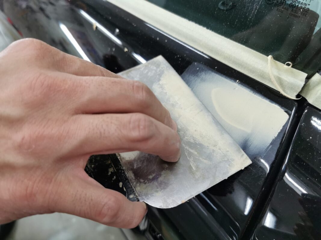Wet-sanding a panel on the Audi TT to bring the surface smooth and level.