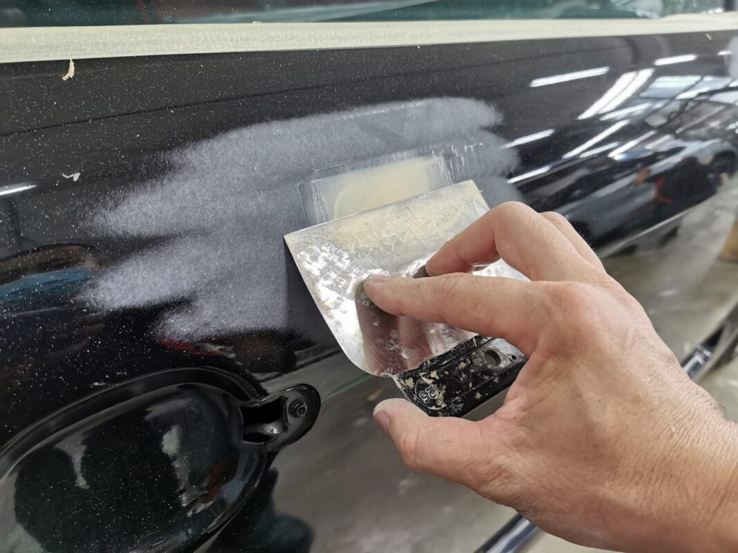 Wet-sanding the Audi TT's door, the guide coat showing the low spots.