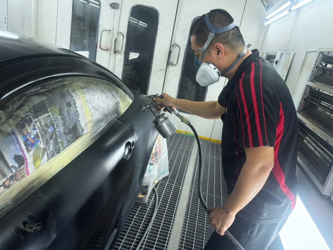 A Revol Carz painter laying the new coat onto the Audi TT in the spray booth.