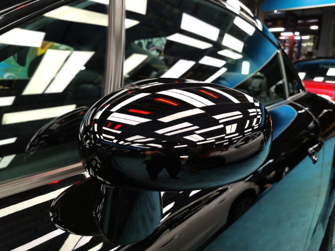 The refitted wing mirror on the Audi TT after painting, reflecting the workshop.