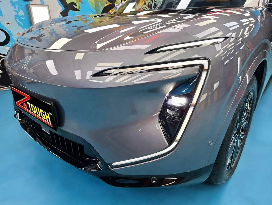 Front of the grey Avatr 07 showing the light bar and headlight, with workshop lights reflected in the bonnet.