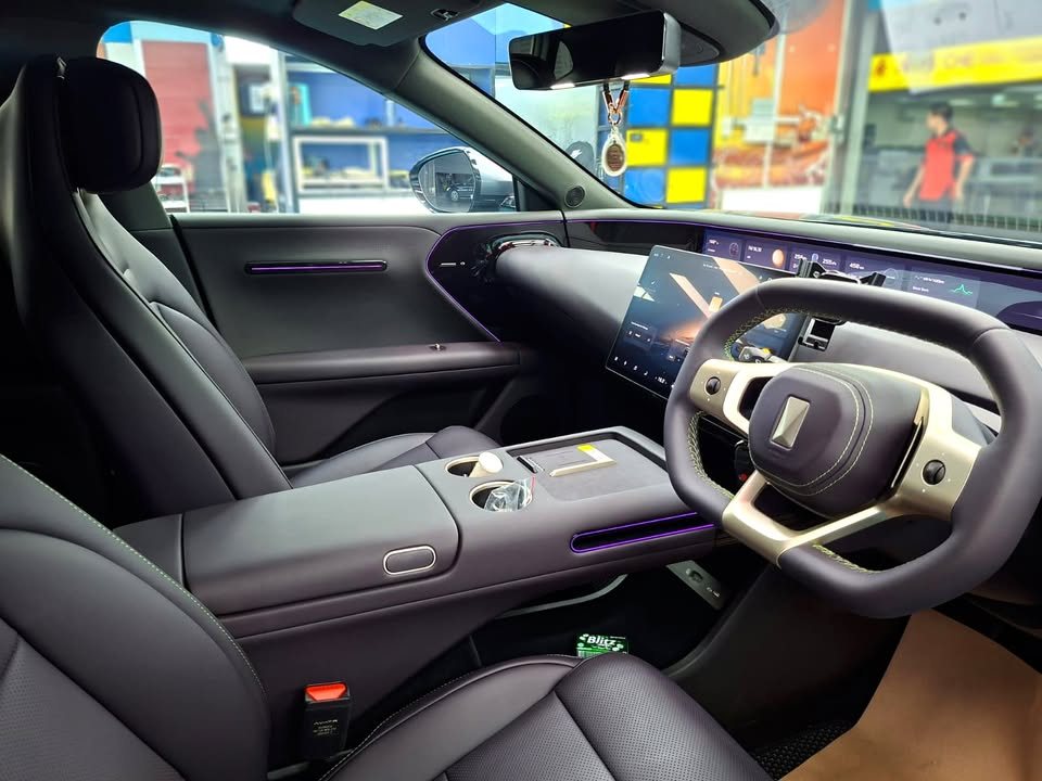 Cleaned cabin with dark leather seats, yoke-style steering wheel and wide dashboard screen.