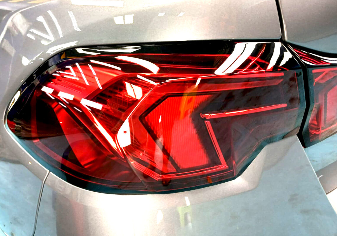 The coated bonnet of the BMW 1 Series under workshop lighting.