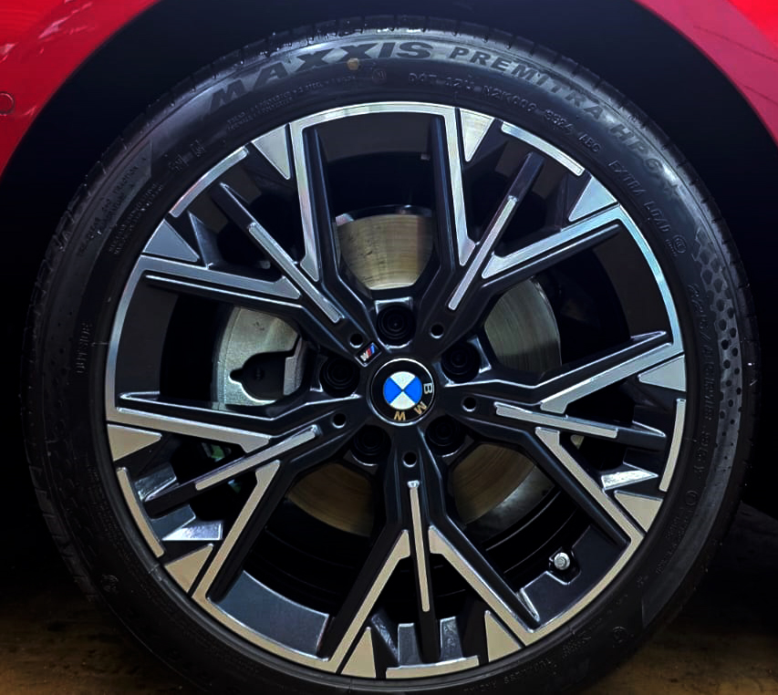 The coated bonnet of the BMW 1 Series under workshop lighting.