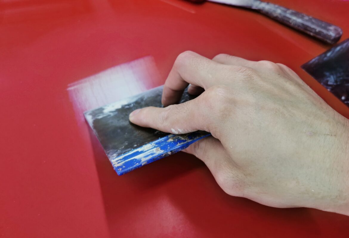 Body filler being applied and worked on the BMW 1 Series to patch surface imperfections.
