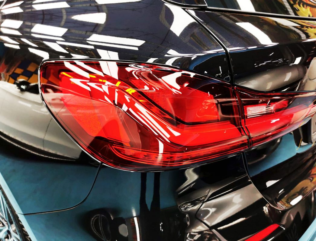The coated bonnet of the BMW 1 Series under workshop lighting.