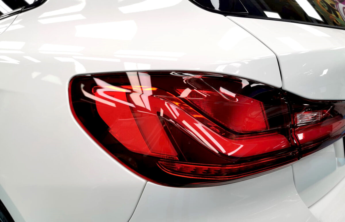 The coated bonnet of the BMW 1 Series under workshop lighting.