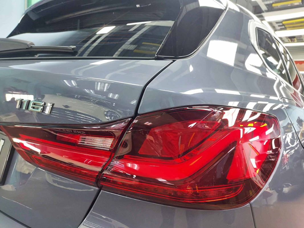 The coated bonnet of the BMW 116i under workshop lighting.