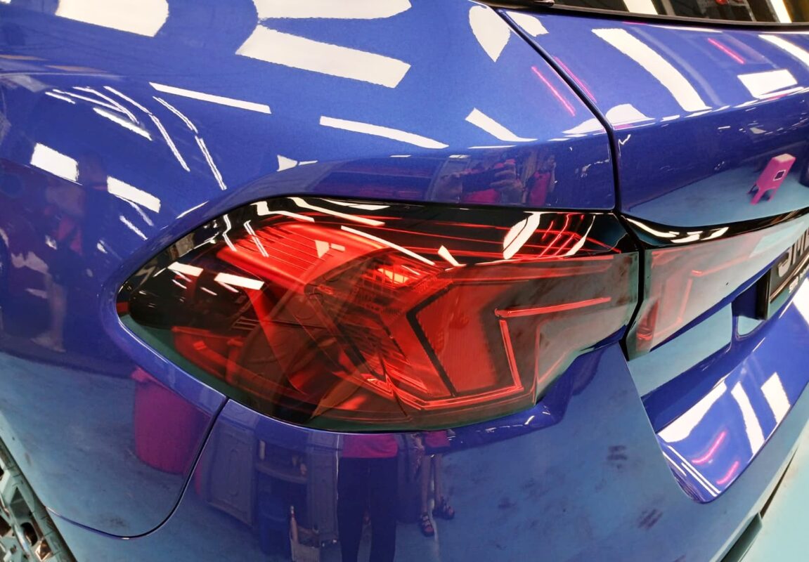 The coated bonnet of the BMW 116i under workshop lighting.
