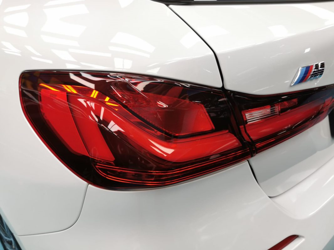 The coated bonnet of the BMW 116i under workshop lighting.