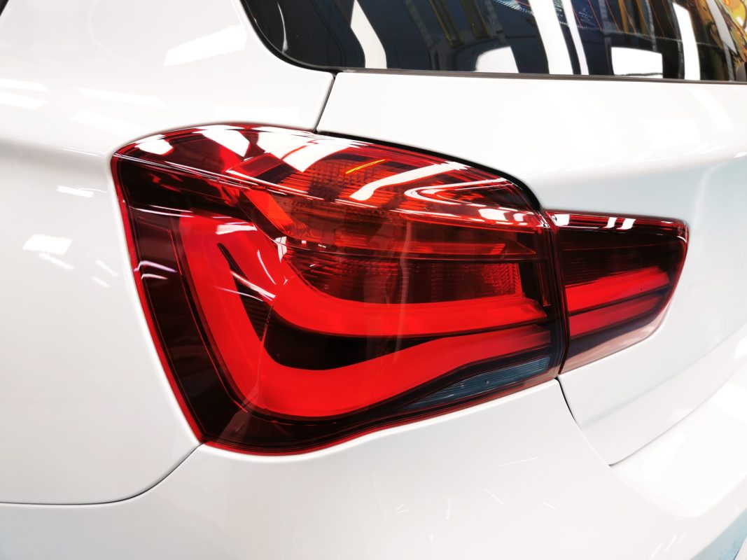 The coated bonnet of the BMW 118i under workshop lighting.