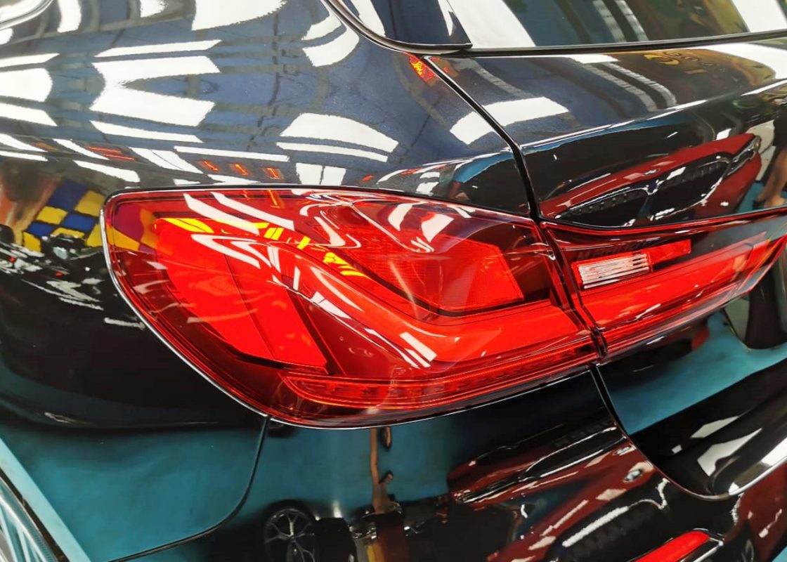 The coated bonnet of the BMW 118i under workshop lighting.