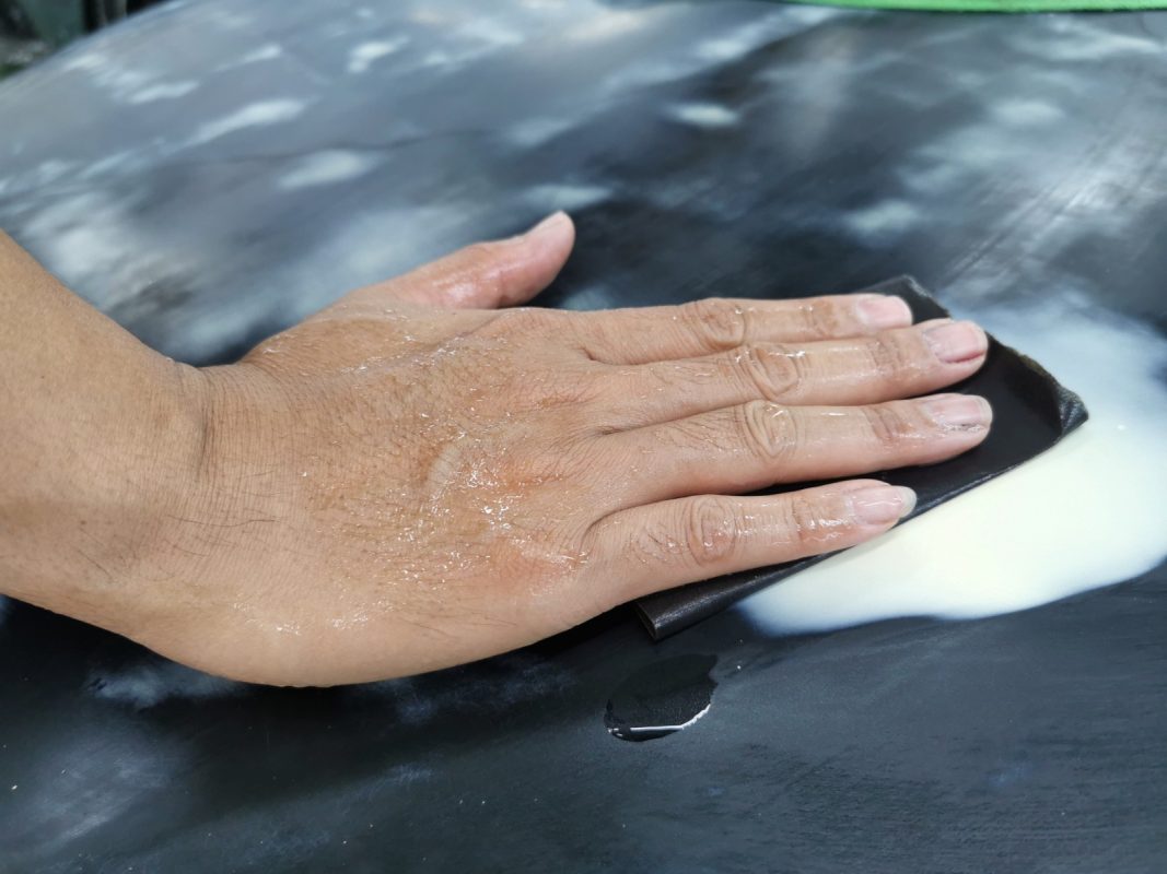 Wet-sanding the 130i's panels to smooth the existing paintwork.