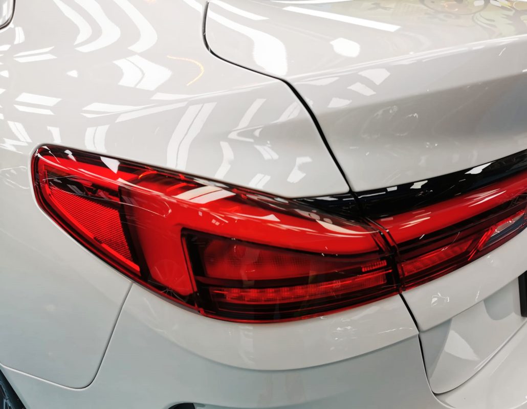 The coated bonnet of the BMW 2 Series under workshop lighting.
