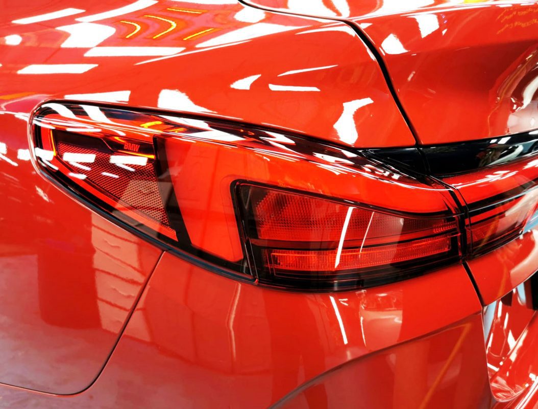 The coated bonnet of the BMW 2 Series under workshop lighting.