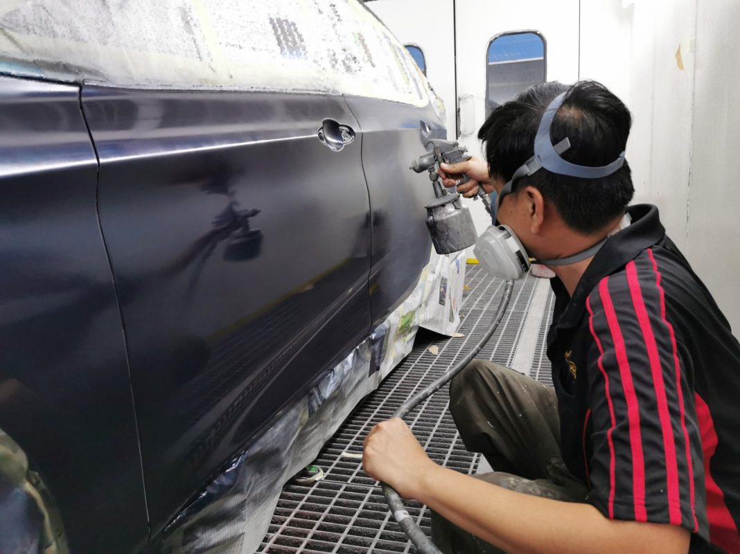 The BMW 2 Series after spraying, with touch-up sanding underway.