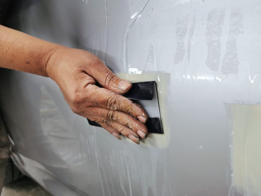 Wet-sanding a primed panel on the BMW 2 Series smooth and level.