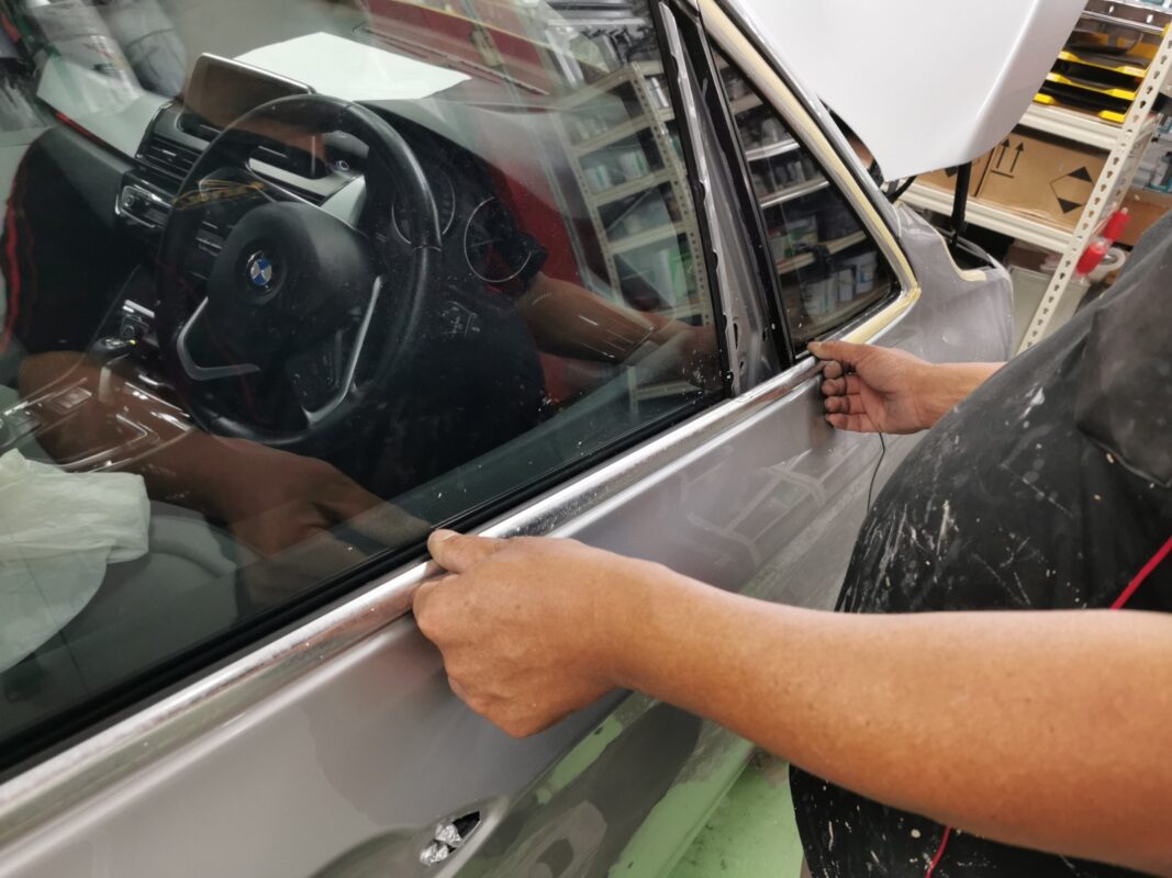 A Revol Carz painter laying the new coat onto the BMW 2 Series in the spray booth.