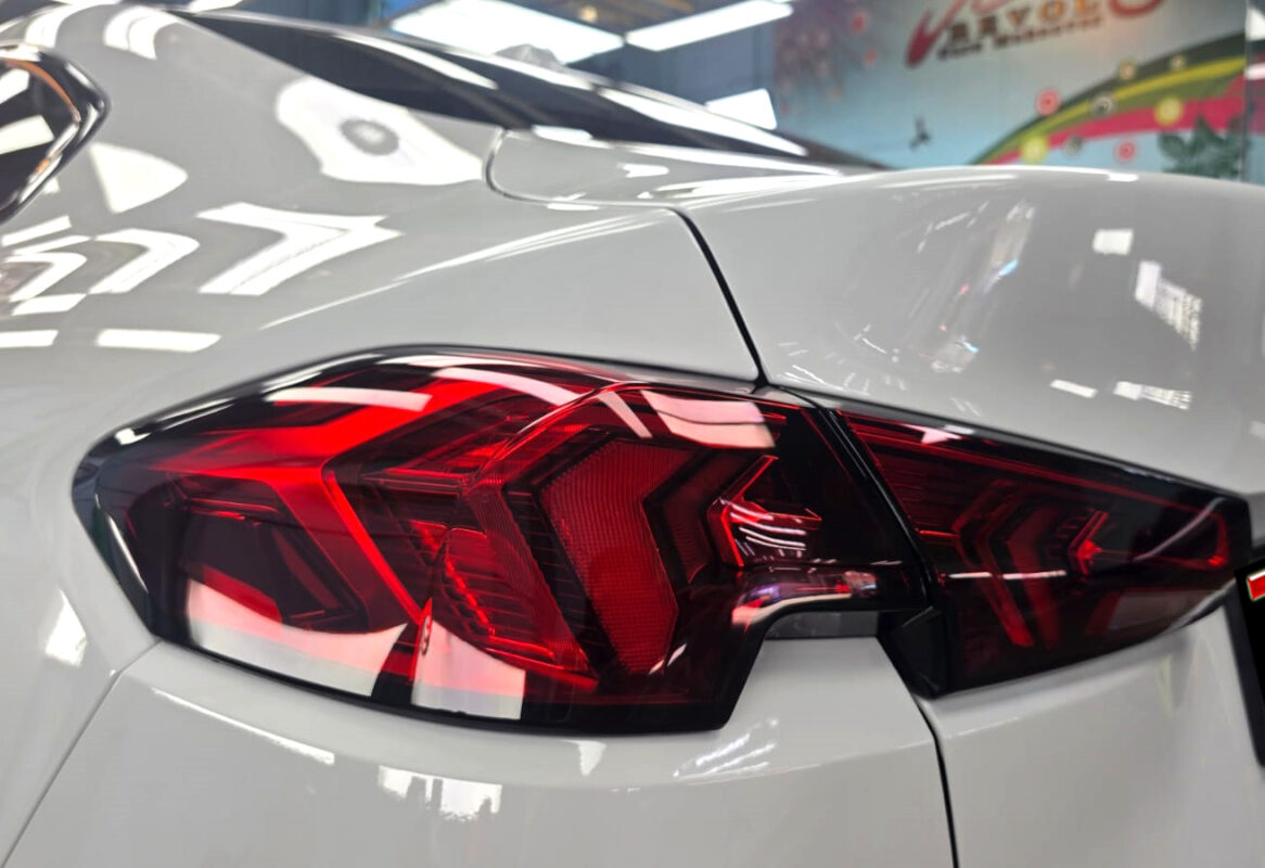 The coated bonnet of the BMW 2 Series under workshop lighting.