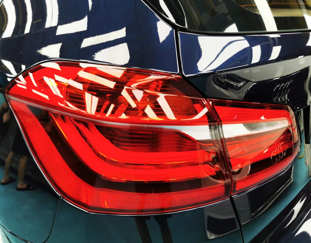 The coated bonnet of the BMW 2 Series under workshop lighting.