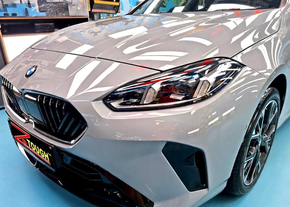 Front of the grey BMW 2 Series showing the kidney grille, headlight and bonnet reflections.
