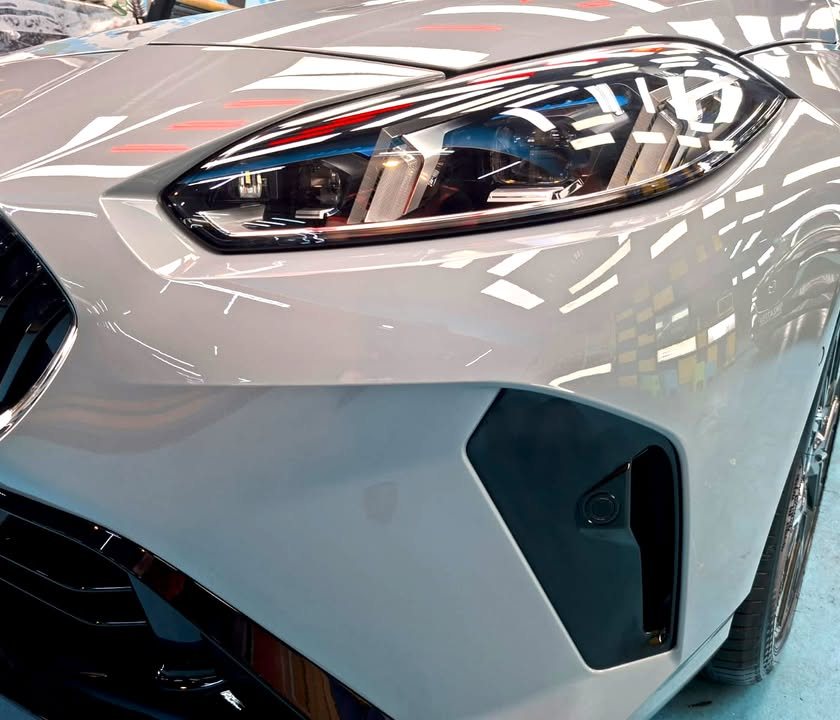 Close-up of the 2 Series headlight and front bumper intake in grey paint.