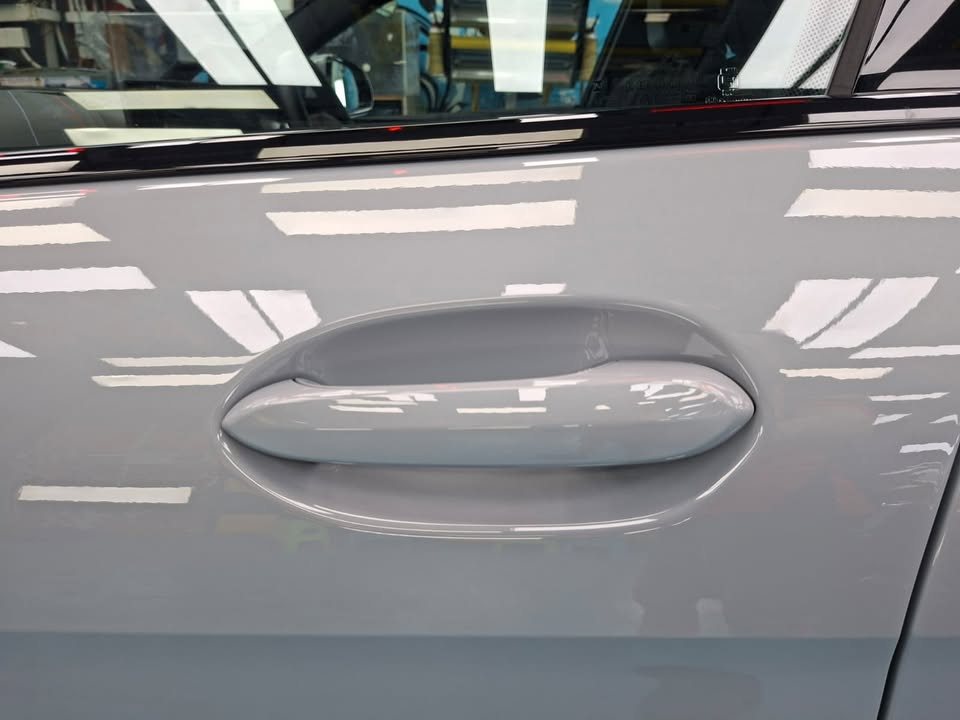 Grey door panel and handle with sharp light reflections.